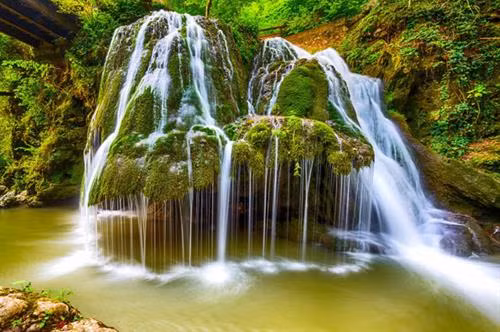 Cảnh đẹp nên thơ của thác nước Bigar tại Romania, nơi những dòng chảy đi qua tảng đá phủ đầy rêu.