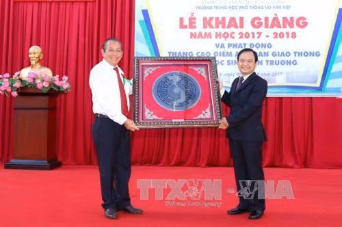 Phó Thủ tướng Thường trực Trương Hòa Bình tặng hoa và quà lưu niệm cho thầy trò Trường THPT Võ Văn Kiệt. Ảnh: Thanh Vũ-TTXVN