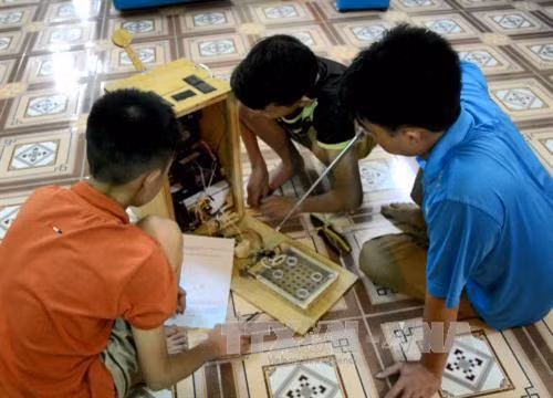 Ma Văn Hùng và Đào Minh Anh cùng thầy giáo hướng dẫn giới thiệu cơ chế hoạt động của "Quạt đa năng". Ảnh: Văn Dũng - TTXVN
