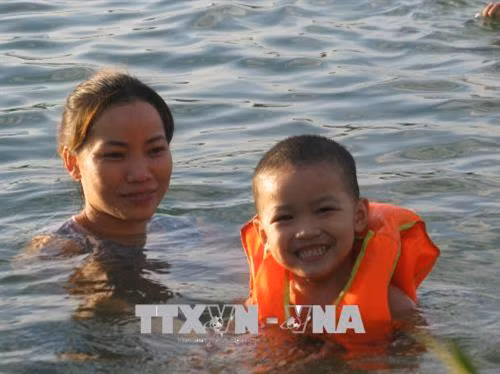 Không chỉ người lớn, trẻ em cũng được mang ra sông tắm. Ảnh: Thanh Hải - TTXVN