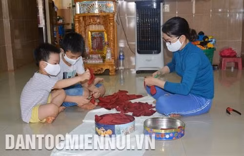 Được nghỉ học, hai con nhỏ của chị Mai Thị Vân, tổ dân phố 3, thị trấn Quảng Phú, huyện Cư M’Gar, tỉnh Đắk Lắk phụ chị may, cắt khẩu trang để phát miễn phí cho người nghèo. Ảnh: Hoài Thu