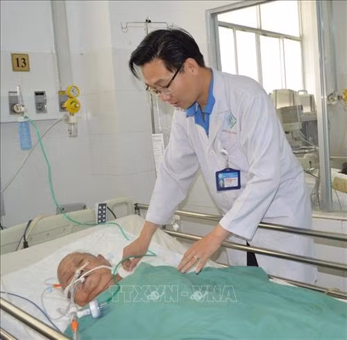 Bác sĩ thăm khám Bà mẹ Việt Nam Anh hùng Đinh Thị Thà sau phẫu thuật. Ảnh: TTXVN phát