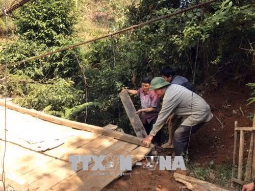 Người có uy tín xã Mường Và, huyện Sốp Cộp vận động, giúp đỡ nhân dân tu sửa cầu treo. Ảnh: Hữu Quyết – TTXVN