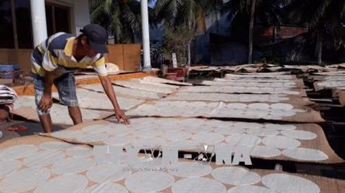 Kiểm tra độ khô bánh phồng Sơn Đốc. Ảnh: Huỳnh Phúc Hậu - TTXVN