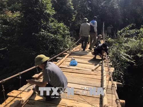 Người có uy tín xã Mường Và, huyện Sốp Cộp vận động, giúp đỡ nhân dân tu sửa cầu treo. Ảnh: Hữu Quyết – TTXVN