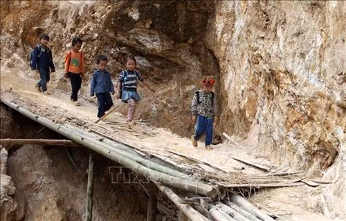 Các em học sinh tại điểm trường Séo Trung Hồ Mông trên đường đi học về qua chiếc cầu tạm. Ảnh: Quốc Khánh - TTXVN
