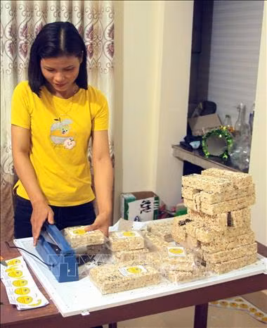 Chị Mai Thị Tuyết Sương đóng gói bánh nổ để bảo quản trước khi xuất bán. Ảnh: Trịnh Bang Nhiệm - TTXVN