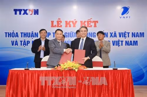 Tổng giám đốc TTXVN Nguyễn Đức Lợi và Chủ tịch Hội đồng thành viên Tập đoàn Bưu chính Viễn thông (VNPT) Trần Mạnh Hùng trao đổi biên bản ký kết hợp tác. Ảnh: Minh Quyết - TTXVN