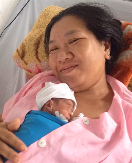 Chị N.T. N. (sinh năm 1996, ngụ tại xã Thạnh Phú, huyện Cờ Đỏ, Cần Thơ) chăm sóc con sau khi được các bác sĩ cứu sống. Ảnh: Thanh Sang - TTXVN