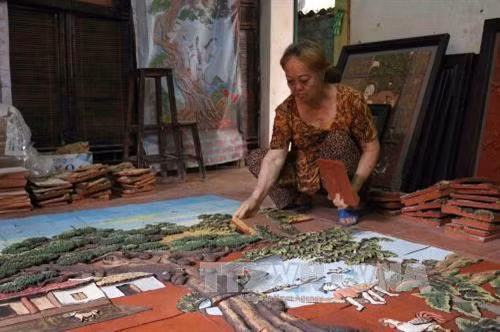 Người thợ ghép các mảnh ghép để tạo thành bức tranh gốm hoàn chỉnh. Ảnh: Thanh Thương - TTXVN