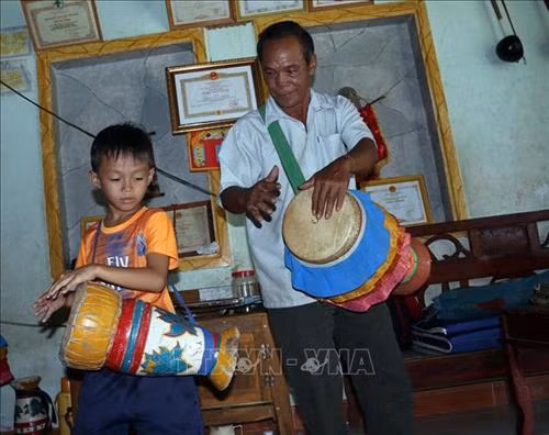 Ông Danh Bê và cháu ngoại Danh Huỳnh Thi (8 tuổi) tập trống. Ảnh: Lê Sen - TTXVN