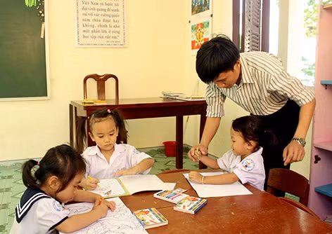 Thầy Hiệp tận tình hướng dẫn học sinh tập viết chữ.