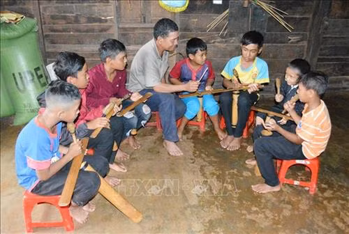 Ông Y’ Gõ Niê dạy đám trẻ buôn Kram đánh chiêng tre. Ảnh: Tuấn Anh – TTXVN