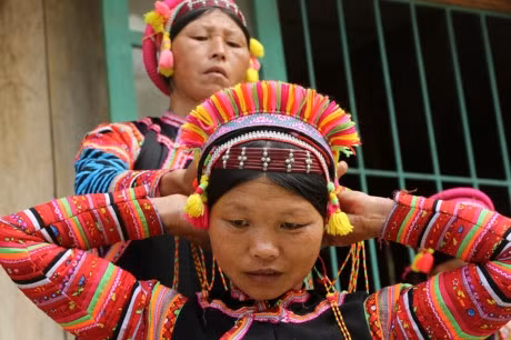 Người La Hủ hay còn gọi là Xá Lá Vàng, Cò Xung, Khù Sung, Khả Quy... hiện có khoảng 10.000 người, sinh sống chủ yếu ở đầu nguồn sông Đà, thuộc huyện Mường Tè, tỉnh Lai Châu. Tuy cuộc sống còn nhiều khó khăn, song đồng bào La Hủ nơi đây vẫn chú trọng gìn giữ bản sắc văn hóa truyền thống, nhất là phụ nữ mặc áo dài tà đen làm nổi bật vóc dáng. Phơ cơ zỡ – tiếng La Hủ có nghĩa là áo dài. Người La Hủ ở Mường Tè thường mặc áo dài tà đen. Các họa tiết, hoa văn... trên mỗi bộ trang phục phụ nữ La Hủ nói lên sự gắn bó giữa cơ thể con người trong sự vận động của cuộc sống với thiên nhiên. Áo dài của người La Hủ ngoài việc mặc ôm sát làm nổi bật đường cong của cơ thể người phụ nữ, còn đẹp ở cách phối màu sắc, cách trang trí và kỳ công của người làm. Mỗi người con gái La Hủ khi đến tuổi thành niên đều tự ý thức may cho mình một chiếc áo dài. Con gái La Hủ thường mặc loại áo cánh tay có nhiều sắc đỏ thể hiện sức sống tươi trẻ và niềm tin yêu cuộc sống. Do hoàn toàn được làm thủ công, nên thời gian để người La Hủ may một chiếc áo dài có khi mất cả tháng mới xong. Duyên dáng thiếu nữ dân tộc La Hủ. Cao nhất trên đầu là vành khăn trang trí với 5 màu sắc. Khăn quấn đầu chủ yếu được làm bằng vải đủ màu và hạt cườm rủ xuống, tạo nét khả ái cho khuôn mặt của người phụ nữ. Để có được bộ trang phục, khăn đội đầu đẹp, đòi hỏi ý tưởng sáng tạo nghệ thuật của người làm. Màu sắc chủ đạo được phối ở cánh tay và điểm xuyết bạc trắng ở thân áo. Làm đẹp cho thân áo còn có sự kết hợp của các hoa văn làm bằng nhôm hình tròn, hình tam giác. Một chiếc áo đẹp còn ở cách trang trí, bài trí những đường diềm tỉ mỉ trên thân áo, tay áo nổi bật lên trên nền vải đen với nhiều màu chỉ đen, đỏ, vàng... May tay áo là công đoạn chiếm nhiều thời gian nhất, có thể tận dụng vải cũ làm lớp lót bên trong, phía ngoài được may ngược. Một ngày với người phụ nữ La Hủ được bắt đầu bằng việc vận trang phục và công đoạn lâu nhất là bện tóc, bọc bằng sợi dây vải màu hồng. Mũ đội đầu Người La Hủ khâu ngực áo rất cẩn thận, đây là công đoạn tách rời những đường viền xếp chồng lên nhau của các loại vải. Việc này không chỉ thể hiện sự khéo léo của những người phụ nữ, mà còn là một trong những nét đẹp trong văn hóa truyền thống của người La Hủ. Vòng quấn đầu được làm từ cây song, mây trên rừng và được điểm tô bằng những chiếc ghim nhôm trang trí. Trang phục truyền thống dân tộc La Hủ đang có nguy cơ mai một, do những thách thức từ điều kiện kinh tế - xã hội.. ...Và việc đồng hóa giữa các dân tộc về phong tục, trang phục. Lớp trẻ dân tộc La Hủ ngày nay thường tự ti khi mặc áo dài dân tộc mình.