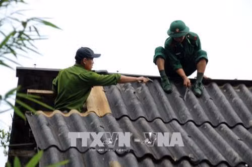 Đoàn viên, thanh niên các đơn vị lực lượng vũ trang hỗ trợ tháo dỡ, lắp mới tấm lợp mái nhà cho người dân. Ảnh: Diệp Anh - TTXVN