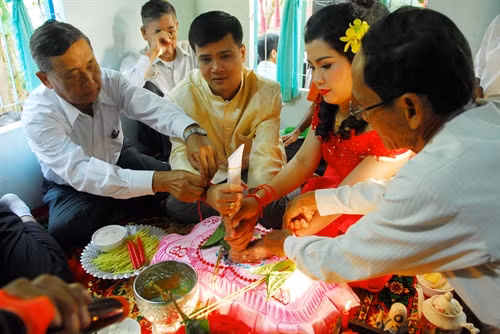 Hai bên gia đình thực hiện “lễ cột chỉ tay” cho cô dâu và chú rể, phía họ nhà trai buộc tay phải của cô dâu còn họ nhà gái buộc tay trái cho chú rể.