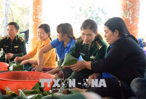 Các thành viên Bộ đội biên phòng, Hội Liên hiệp phụ nữ và Đoàn Thanh niên tỉnh Gia Lai gói bánh chưng tặng bà con vùng biên giới Ia Mơ. Ảnh: Hoài Nam – TTXVN