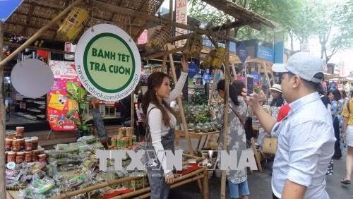 Các bạn trẻ chụp hình lưu niệm tại gian hàng bánh Tét trên Đường sách Nguyễn Văn Bình. Ảnh: Gia Thuận - TTXVN