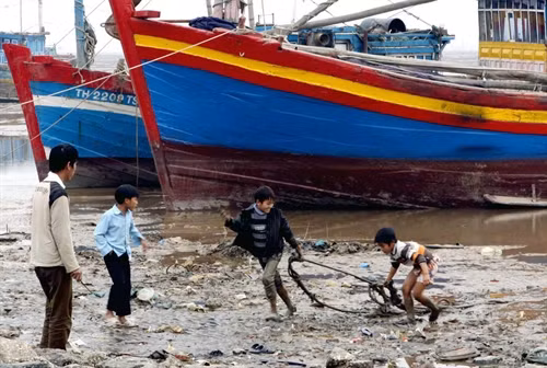 Trẻ em xã Ngư Lộc nhặt phế thải trên bãi biển. Ảnh: Dương Ngọc - TTXVN.