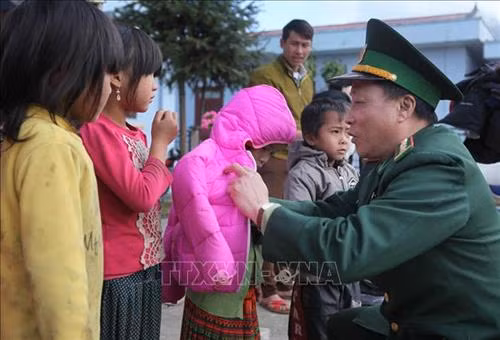 Đại tá Nguyễn Tất Hậu, Phó Chính ủy Bộ chỉ huy Bộ đội Biên phòng tỉnh Lai Châu, tặng áo ấm cho học sinh Trường PTDTBT tiểu học xã Tung Qua Lìn. Ảnh: Quý Trung – TTXVN
