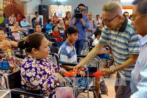 Các thành viên Hội từ thiện Benevolence Charity Hall Limited (Hong Kong, Trung Quốc) cùng ban tổ chức trao tặng xe lăn và quà cho người khuyết tật nghèo, nạn nhân da cam tại Thành phố Hồ Chí Minh. Ảnh: Thế Anh - TTXVN.