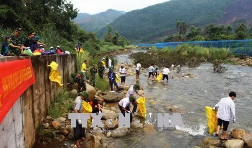 Bộ đội biên phòng cửa khẩu Hoành Mô cùng nhân dân dọn vệ sinh môi trường trên sông biên giới Đồng Mô. Ảnh: Văn Đức – TTXVN