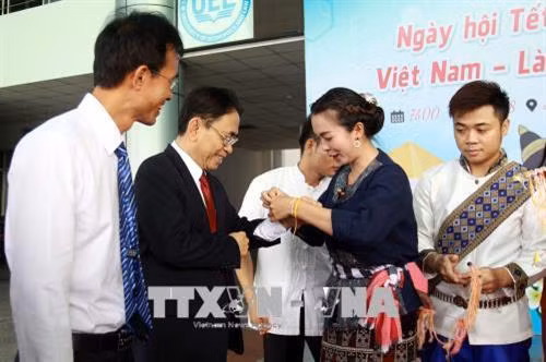 Nghi thức buộc chỉ cổ tay chúc phúc, cầu bình an trong năm mới của sinh viên Lào. Ảnh: Thanh Vũ-TTXVN