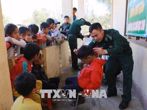 Đội công tác địa bàn Đồn Biên phòng Sêrêpốk cắt tóc cho trẻ em buôn Yang Lành, xã Krông Na, huyện Buôn Đôn. Ảnh: Dương Giang - TTXVN