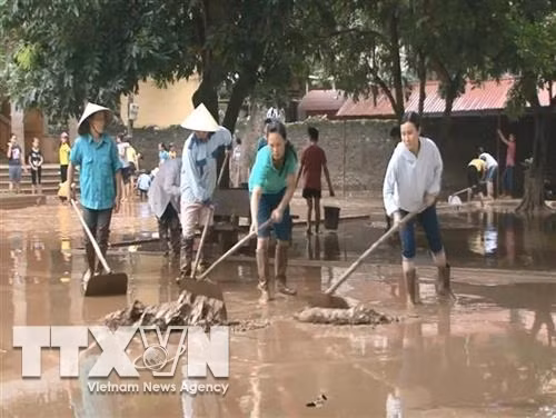 Thu dọn bùn đất tại Trường Tiểu học Vĩnh Yên. Ảnh: Khiếu Tư-TTXVN