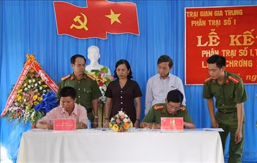 Đại diện Phân trại số 1, trại giam Gia Trung và làng ChRơng II ký kết văn bản kết nghĩa. Ảnh: Hoài Nam – TTXVN.