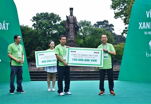 Đại diện Công ty AmWay Việt Nam (bên phải) trao tặng bảng tượng trưng số tiền 100 triệu đồng ủng hộ cho Quỹ "Vì nỗi đau da cam" của TTXVN tại chương trình. Ảnh: Minh Quyết – TTXVN