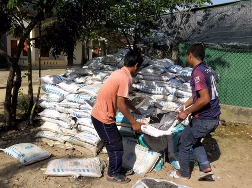 Không có ruộng, người dân chất đống phân bón được hỗ trợ. Ảnh: Phước Ngọc-TTXVN