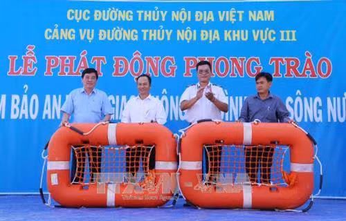 Trao áo phao cứu hộ cho những chủ phương tiện giao thông đường thủy. Ảnh: Nam Thái – TTXVN