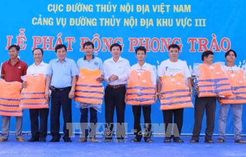 Trao áo phao cứu hộ cho chủ phương tiện giao thông đường thủy. Ảnh: Nam Thái – TTXVN