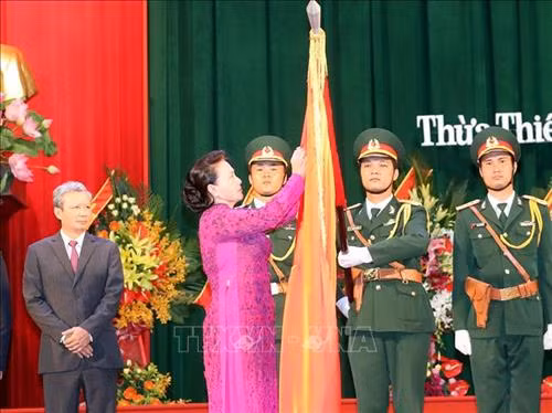 Chủ tịch Quốc hội Nguyễn Thị Kim Ngân gắn Huân chương Độc lập hạng Nhất lên cờ truyền thống của tỉnh Thừa Thiên Huế. Ảnh: Trọng Đức - TTXVN