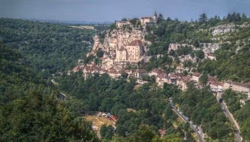 Ngôi làng cổ Rocamadour được xây dựng trên vách núi ở vùng Occitanie, miền tây nam Pháp. Từ thời Trung cổ, ngôi làng đã thu hút những người hành hương từ khắp châu Âu tới đây tham quan các công trình lịch sử và nhà thờ Đức Mẹ Maria. Thánh St Amator đã sống và qua đời tại ngôi làng Rocamadour ngay sau khi ông rời khỏi Jerusalem. Truyền thuyết kể rằng sau khi thi thể thánh St Amator được phát hiện, một số phép màu đã xảy ra. Ngôi làng bắt đầu thu hút nhiều người hành hương và ủng hộ từ các nhà vua Pháp, giúp ngôi làng xây dựng các nơi thờ cúng. Một lý do khác khiến Rocamadour thu hút nhiều du khách là phong cảnh đẹp. Các công trình cổ được xây dựng trên vách núi nhìn xuống sông Alzou. Các tòa nhà trong làng có độ cao cách mặt đất phía dưới khoảng 120m. Trung tâm của ngôi làng là nhà thờ hành hương Notre Dame, được cải tạo lại từ công trình gốc được xây dựng từ năm 1479. Ngoài ra, Rocamadour còn có nhiều công trình cổ kính khác được xây dựng từ thời Trung cổ. Du khách tham quan dọc một con đường dốc tại ngôi làng cổ Rocamadour. Những ngôi nhà được xây dựng trên vách đá dựng đứng.