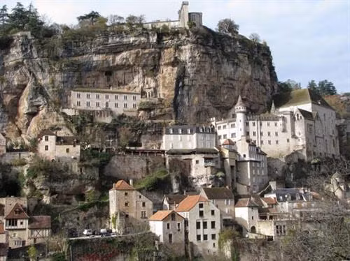 Ngôi làng cổ Rocamadour được xây dựng trên vách núi ở vùng Occitanie, miền tây nam Pháp. Từ thời Trung cổ, ngôi làng đã thu hút những người hành hương từ khắp châu Âu tới đây tham quan các công trình lịch sử và nhà thờ Đức Mẹ Maria. Thánh St Amator đã sống và qua đời tại ngôi làng Rocamadour ngay sau khi ông rời khỏi Jerusalem. Truyền thuyết kể rằng sau khi thi thể thánh St Amator được phát hiện, một số phép màu đã xảy ra. Ngôi làng bắt đầu thu hút nhiều người hành hương và ủng hộ từ các nhà vua Pháp, giúp ngôi làng xây dựng các nơi thờ cúng. Một lý do khác khiến Rocamadour thu hút nhiều du khách là phong cảnh đẹp. Các công trình cổ được xây dựng trên vách núi nhìn xuống sông Alzou. Các tòa nhà trong làng có độ cao cách mặt đất phía dưới khoảng 120m. Trung tâm của ngôi làng là nhà thờ hành hương Notre Dame, được cải tạo lại từ công trình gốc được xây dựng từ năm 1479. Ngoài ra, Rocamadour còn có nhiều công trình cổ kính khác được xây dựng từ thời Trung cổ. Du khách tham quan dọc một con đường dốc tại ngôi làng cổ Rocamadour. Những ngôi nhà được xây dựng trên vách đá dựng đứng.