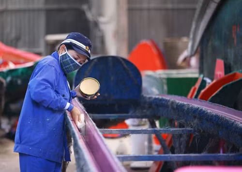 Công nhân hoàn thiện thân vỏ cano. Ảnh: Nam Thái - TTXVN