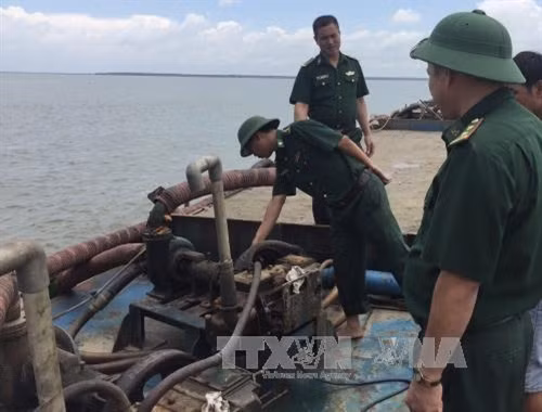 Lực lượng biên phòng Thành phố Hồ Chí Minh kiểm tra phương tiện khai thác cát trái phép bị thu giữ. Ảnh: Thành Chung - TTXVN