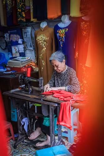 Bà Lê Thị Quyến, chủ hiệu áo dài Vinh Trạch ở phố Lương Văn Can, quận Hoàn Kiếm dù tuổi cao nhưng vẫn miệt mài bên bàn máy để trực tiếp làm ra những sản phẩm áo dài mang đúng thương hiệu của Trạch Xá.