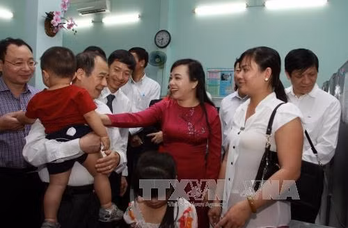 Bộ trưởng Nguyễn Thị Kim Tiến thăm hỏi người dân đưa con đến tiêm chủng tại Viện Pastuer Hồ Chí Minh. Ảnh: Phương Vy-TTXVN.