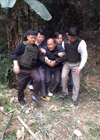 Công an huyện Tân Uyên bắt giải đối tượng Hạng A Lau vận chuyển 39 bánh heroin có súng trốn chạy vào rừng. Ảnh: TTXVN phát