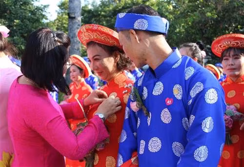 Trao tặng Huy hiệu thành phố cho các cặp đôi tham gia lễ cưới tập thể. Ảnh: Xuân Dự - TTXVN