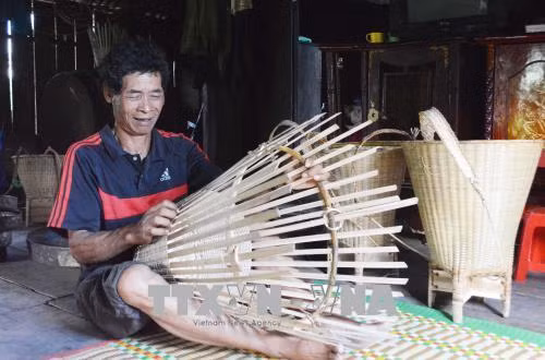 Ông Y’ Quyết Liêng đan gùi truyền thống của người M’nông. Ảnh: Tuấn Anh – TTXVN
