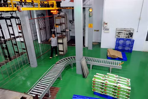 Vải sau khi chiếu xạ xong được chuyển ra bằng băng chuyền. Ảnh: Quang Quyết-TTXVN