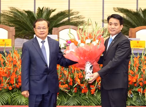 Đồng chí Phạm Quang Nghị (bên trái), Ủy viên Bộ Chính trị, Chỉ đạo Thành ủy Hà Nội tặng hoa chúc mừng tân Chủ tịch Ủy ban nhân dân thành phố Hà Nội Nguyễn Đức Chung. Ảnh: An Đăng - TTXVN