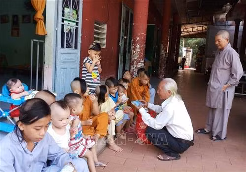 Thầy giáo Nguyễn Tiến Minh tặng quà cho các em nhỏ. Ảnh: Lê Xuân-TTXVN