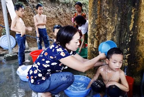 Cô giáo Nguyễn Thị Mỹ tắm cho học sinh bán trú. Ảnh: Đinh Đức Tưởng - TTXVN