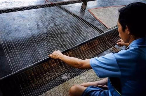 Nhiều hộ dân vẫn giữ phương pháp dệt chiếu thủ công bằng tay. Ảnh: Nam Thái - TTXVN
