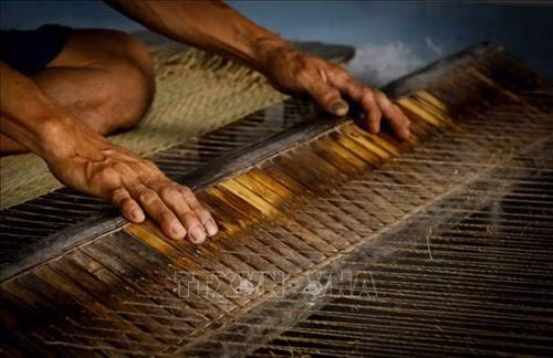 Nhiều hộ dân vẫn giữ phương pháp dệt chiếu thủ công bằng tay. Ảnh: Nam Thái - TTXVN